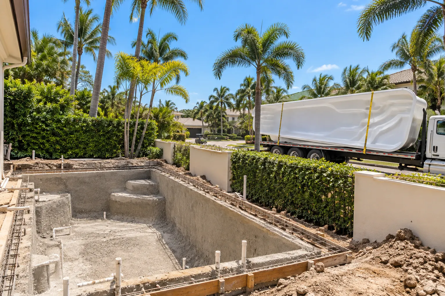 Concrete pool shell next to a fiberglass shell on a truck